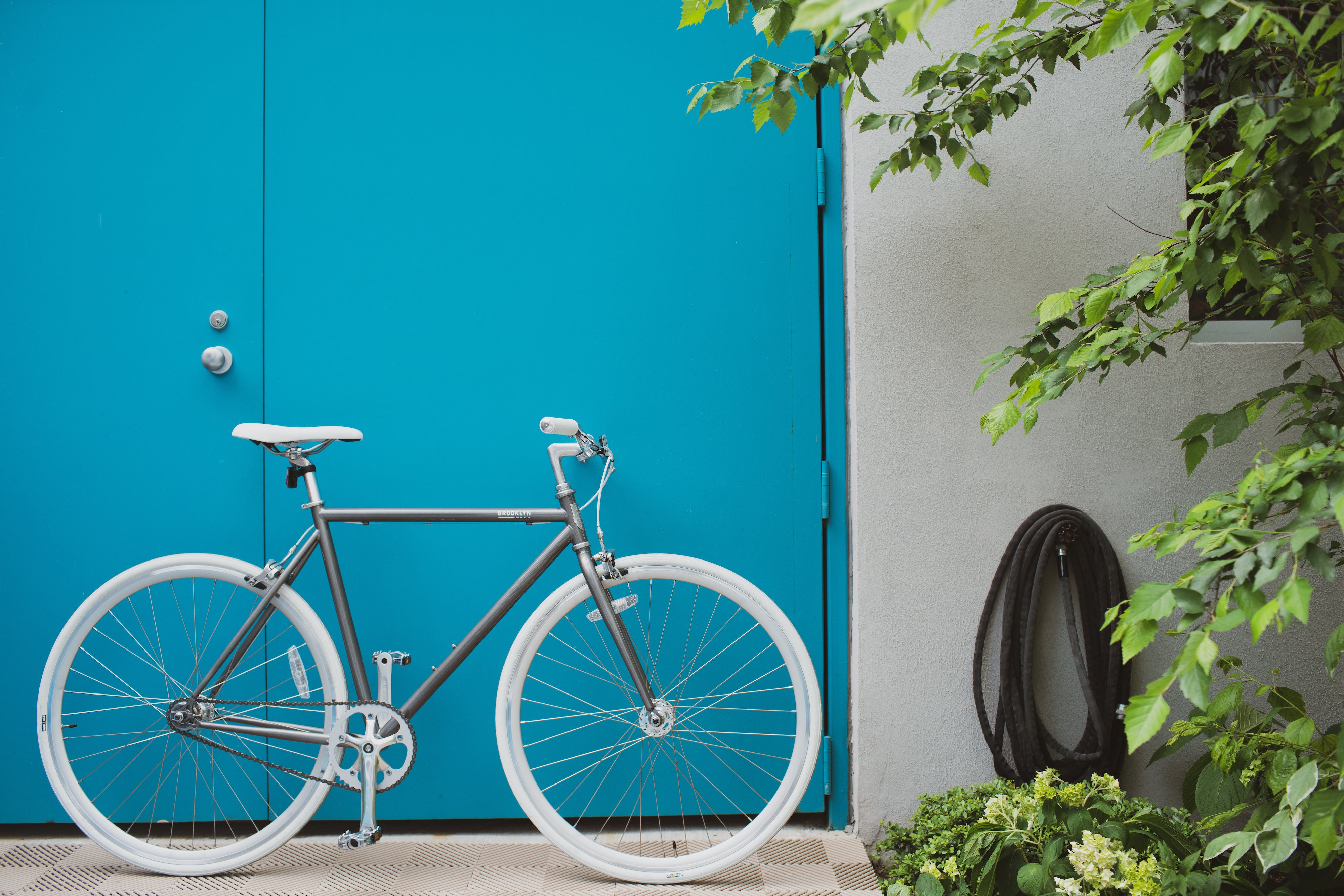 Raw silver Wythe bike against aqua colored door