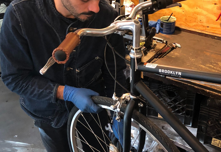 A partner shop mechanic truing a wheel on a Brooklyn Bicycle Co. bike